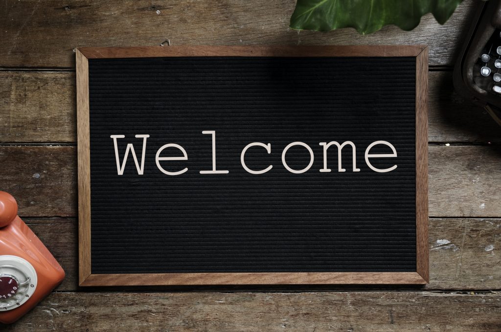 A black board on a desk, showing the word "Welcome".