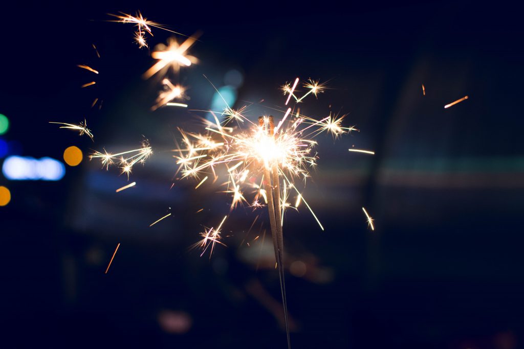 Two sparklers held in a hand against a dark background