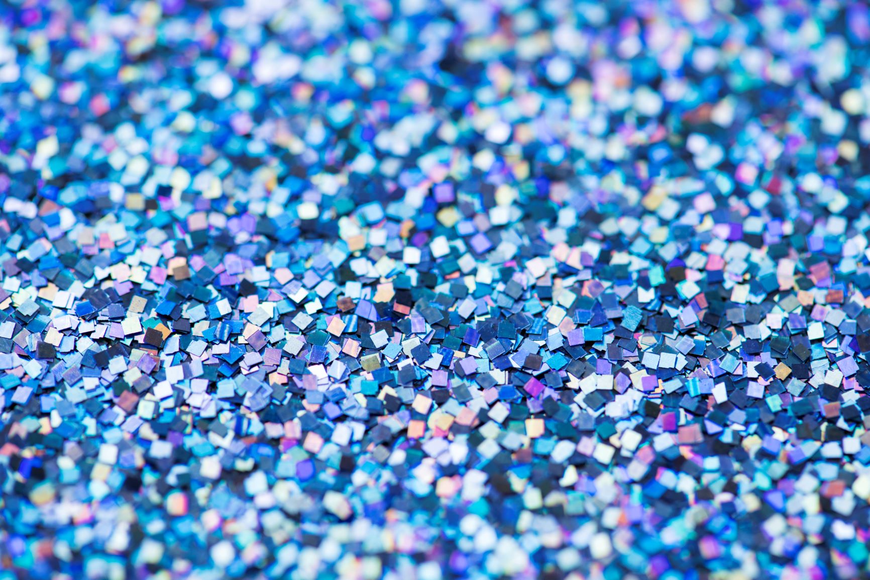 Sequins and glitter of many different shades of blue scattered on a surface.