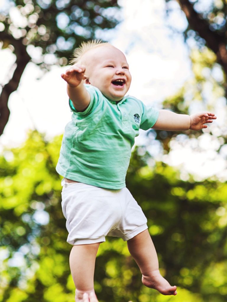 A smiling and laughing baby being thrown in the air