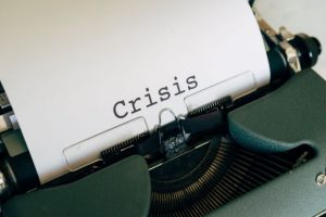 A typewriter with the word 'crisis' in the centre of a white sheet of paper