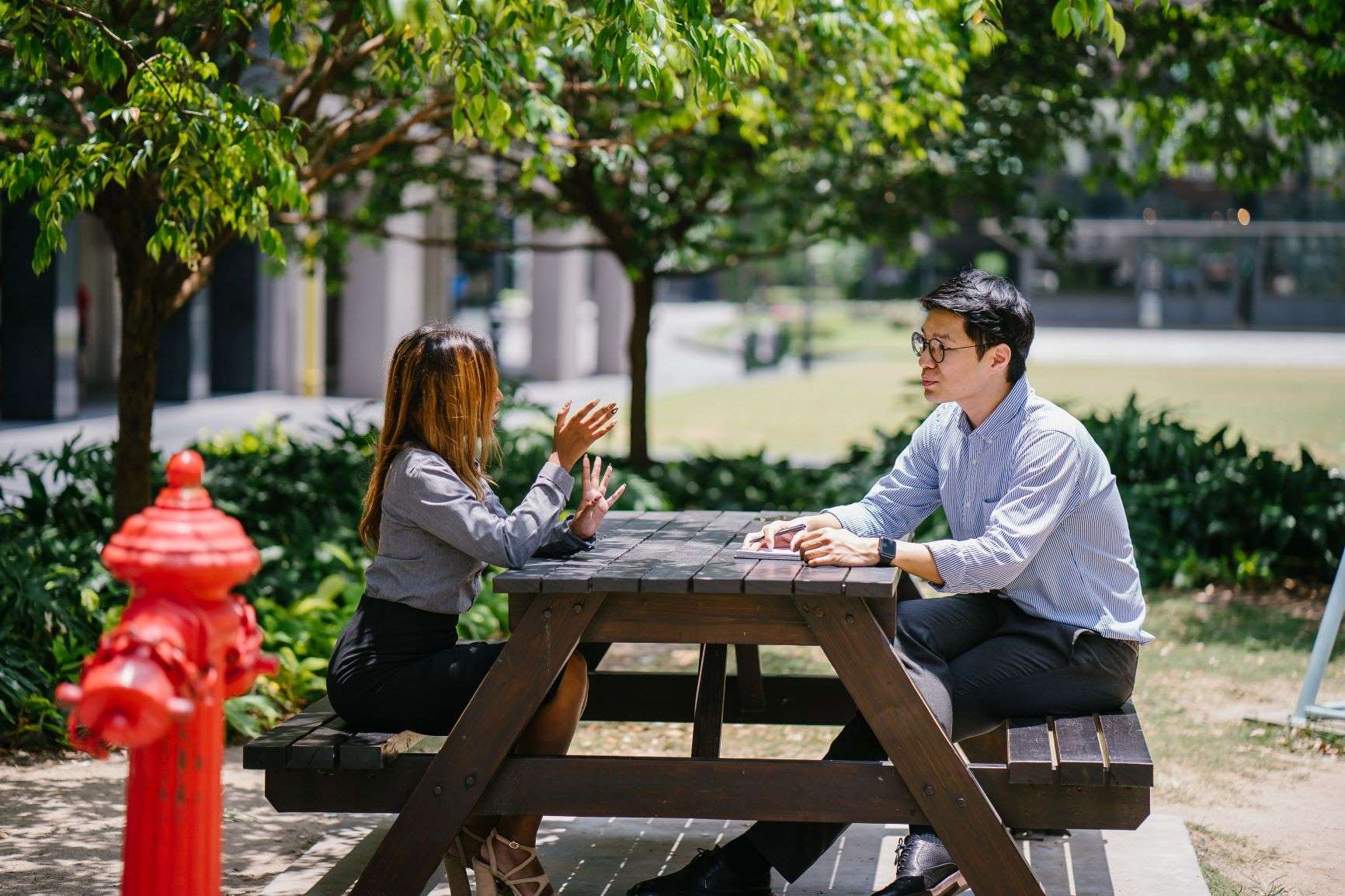 A woman and man sitting at an outdoor table, deep in conversation