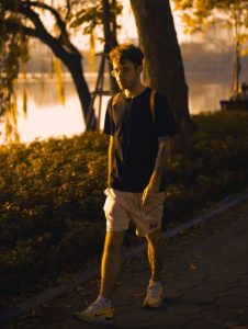 A man walking in a park at sunset, wearing earphones