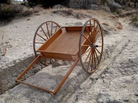 Photo of an empty wagon cart with wheels stuck in a rut