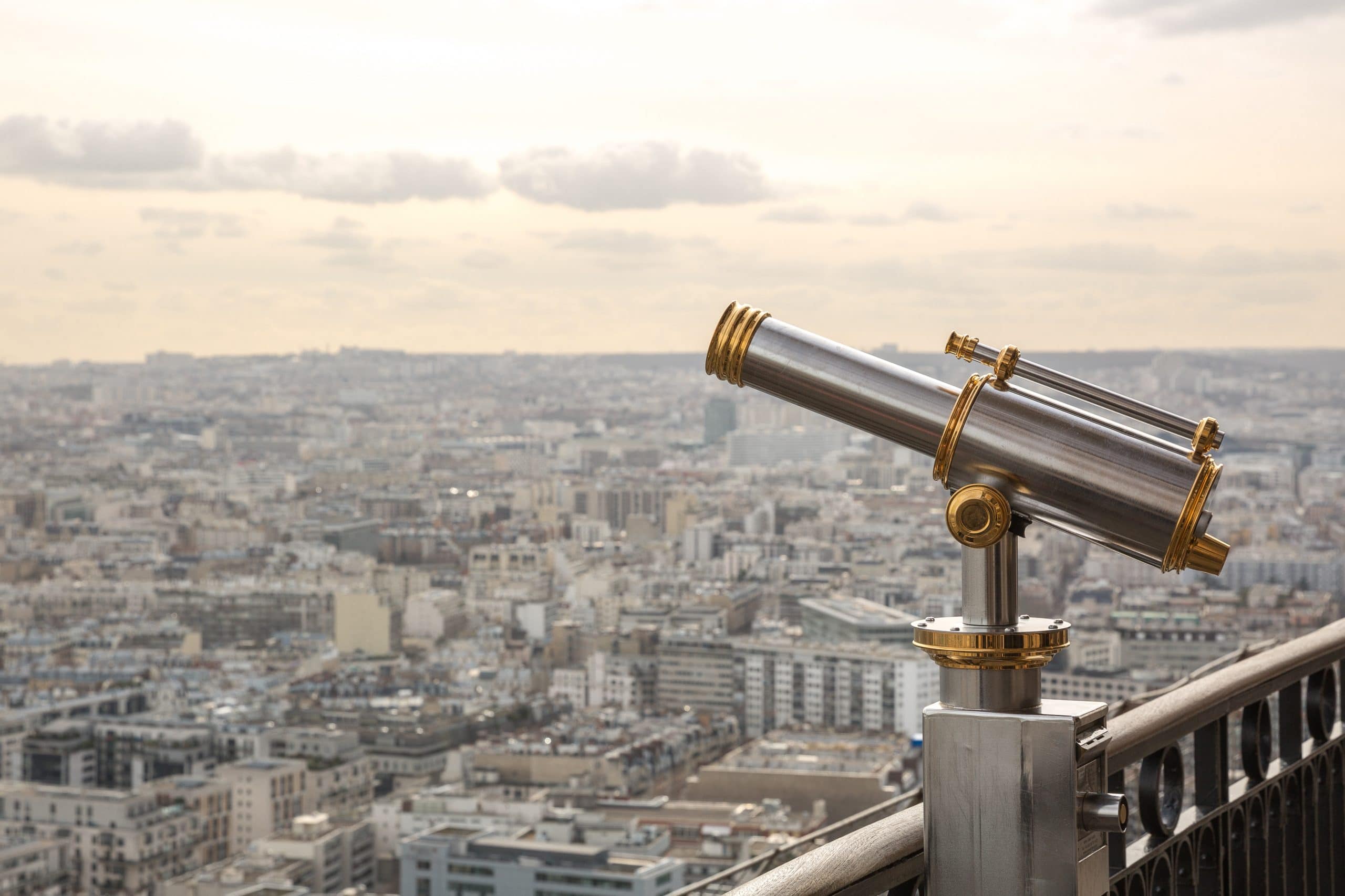 A telescope on a balcony above a cityscape