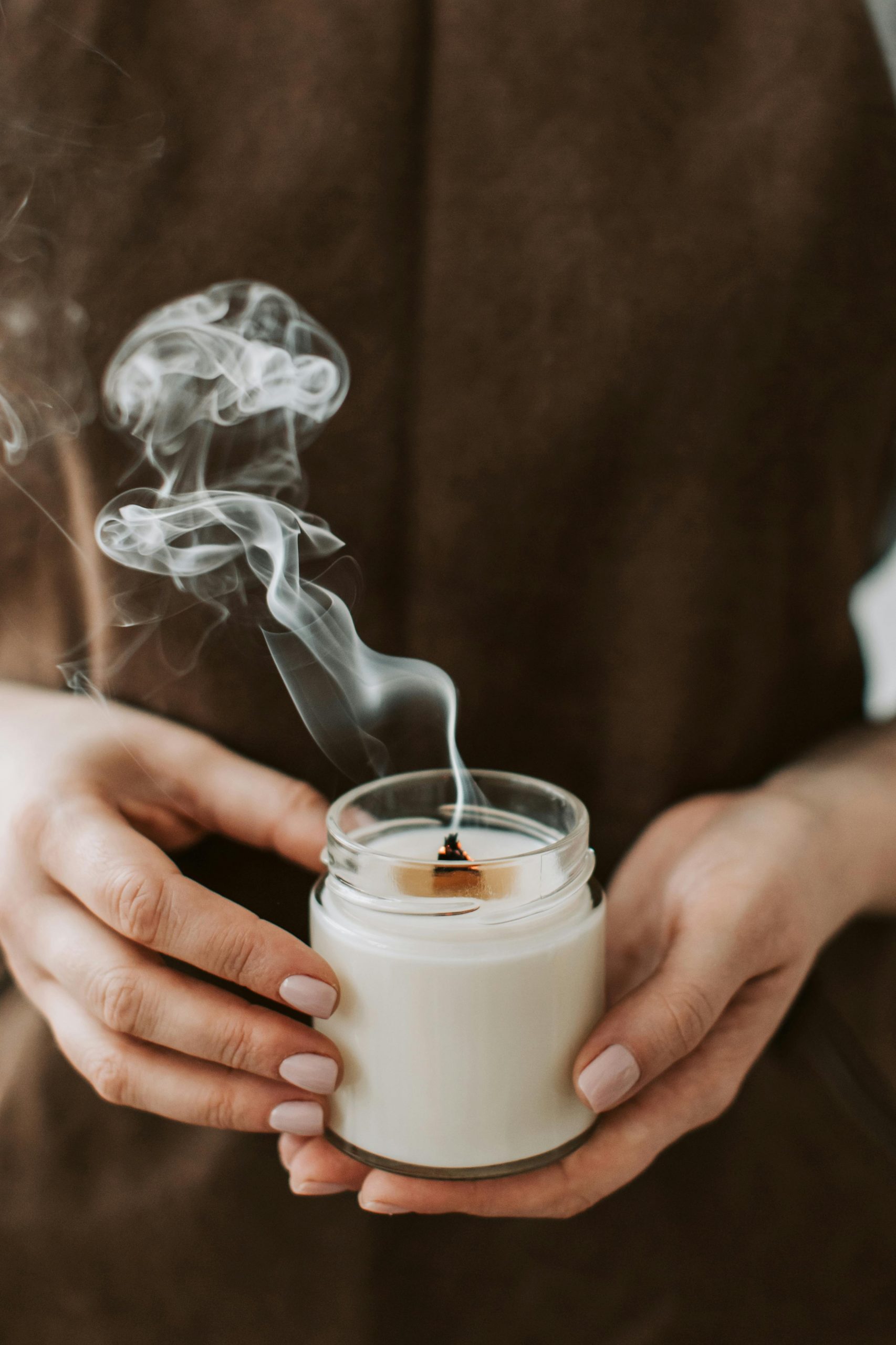Person holding smoking candle in jar