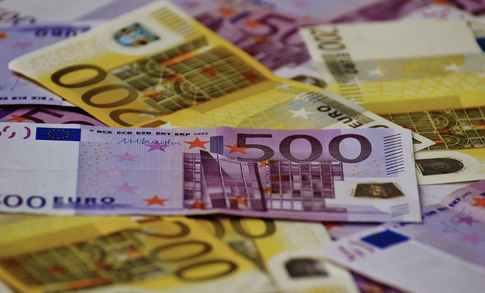 Pixabay on Pexels ID: A pile of Euro currency spread across a table. Denominations visible are €500 and €200.