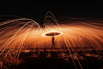 A long exposure photograph of a person swinging a large sparkler over their head