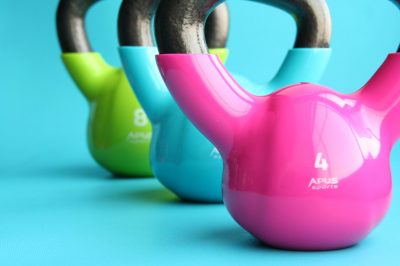 Picture of a pink, blue and green strength-training kettlebell on a blue background
