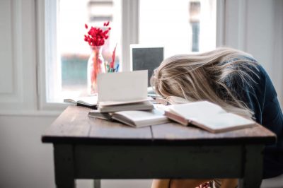Woman with her head on her desk, looking fatigued