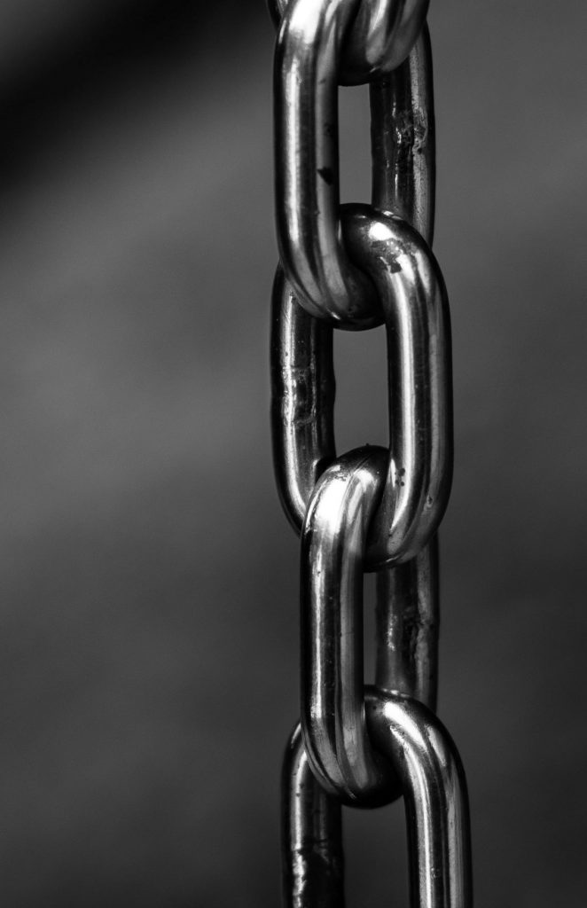 Greyscale photo of a heavy chain dangling vertically. Image credit: Pexels