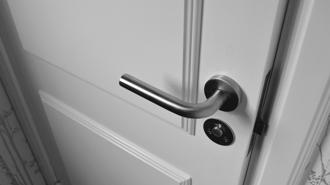 A black and white photograph of a door standing slightly open