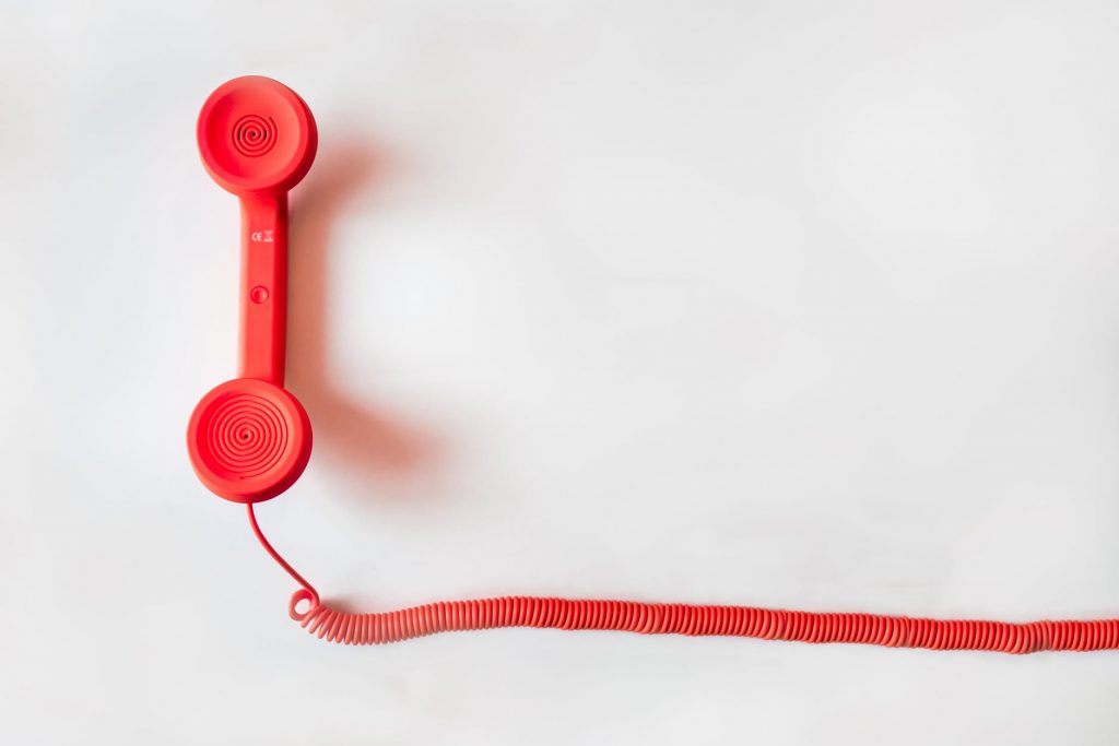A old-style red telephone handset with cord