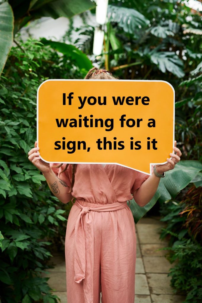 A woman holding a sign saying 'If you were waiting for a sign, this is it'