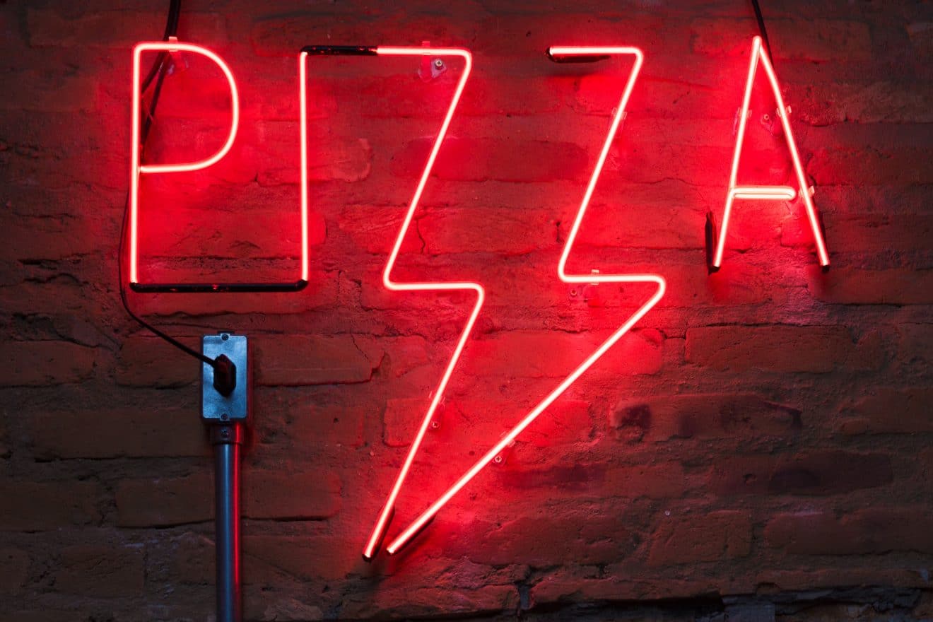 Red neon sign saying "Pizza", with the Z's forming a lightning bolt